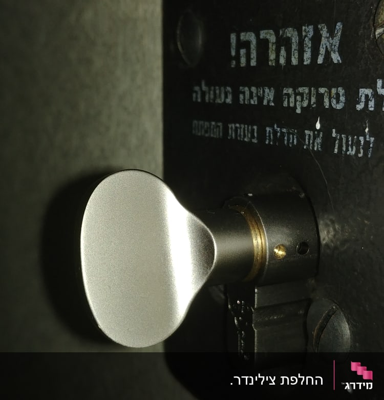 ידית מתכת של מנעול על דלת עם כיתוב בעברית